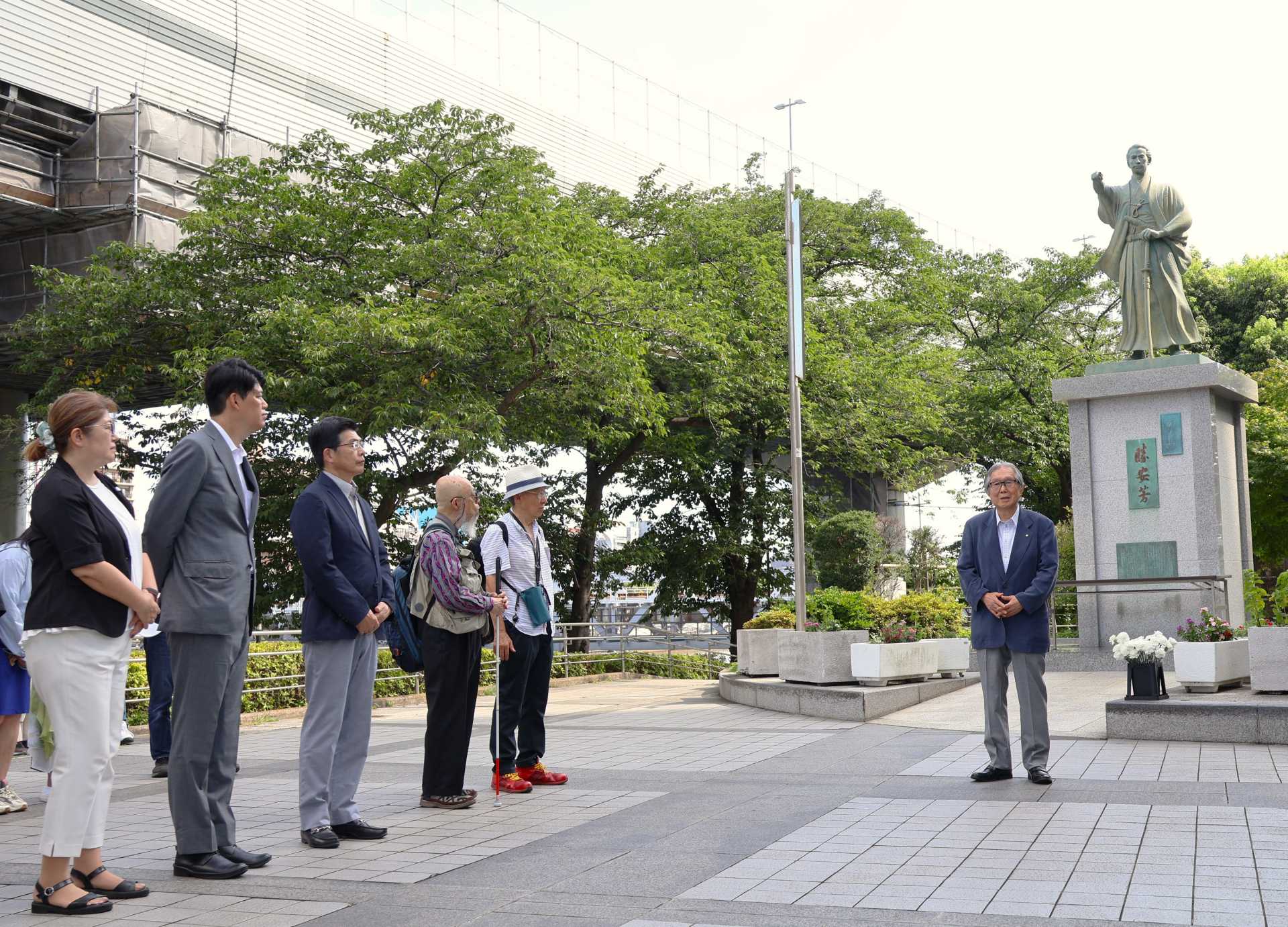 勝海舟の銅像の前で挨拶する勝海舟顕彰会・廣田健史会長（右、左から一般社団法人墨田区観光協会・森山育子理事長、墨田区議会・佐藤篤議長、墨田区・山本亨区長＝うるおい広場で）