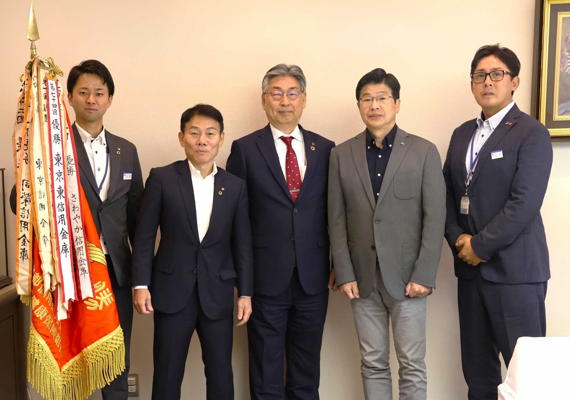 「第７４回東京都信用金庫野球大会」での５７年ぶり優勝を墨田区・山本亨区長（右から２人目）に報告する東京東信用金庫・吉田誠理事長（同３人目、同４人目は野球部部長・湯浅博常勤理事、右は玉村和啓監督、左はエース・石田海斗）