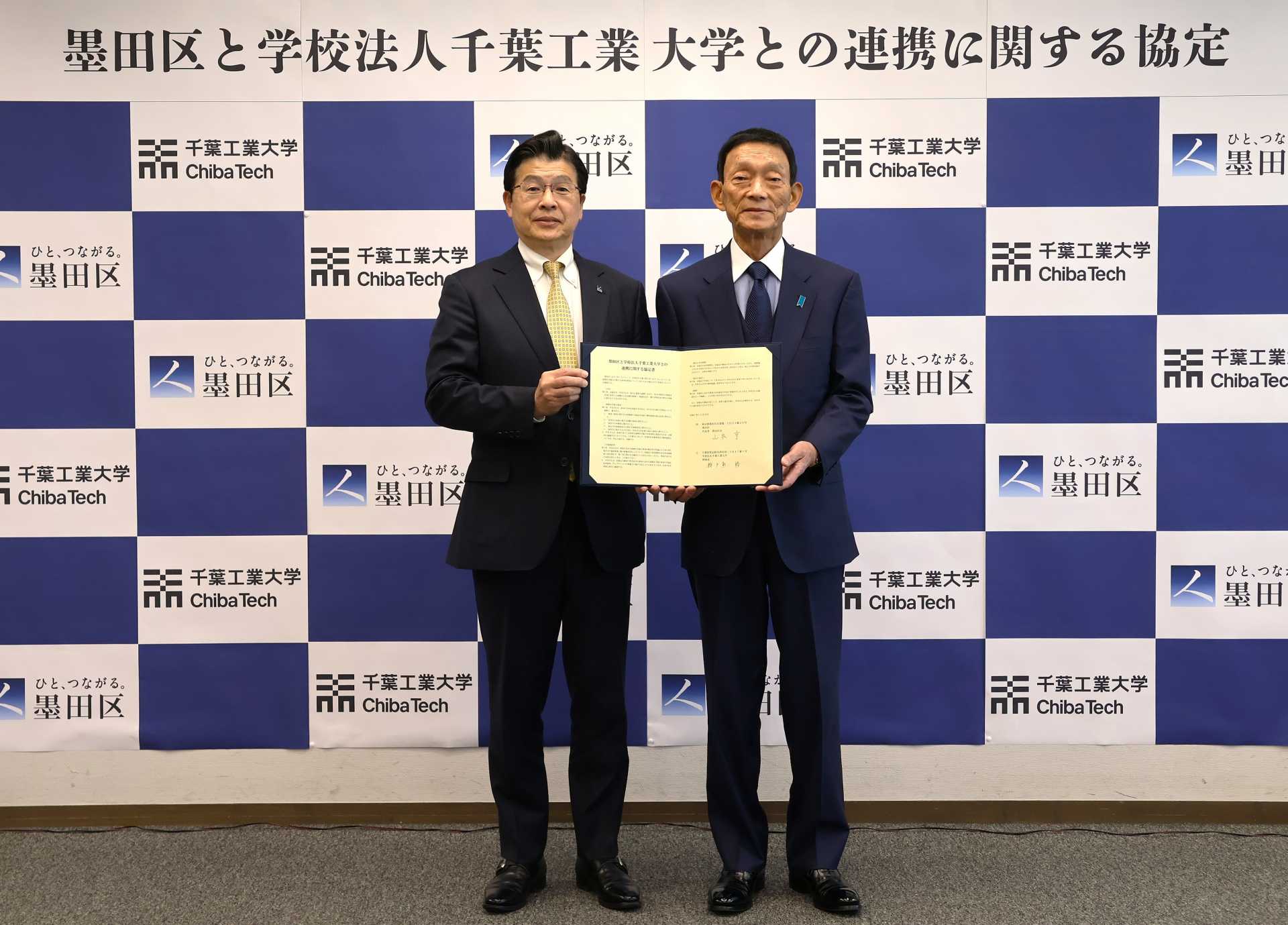 協定書を手にする山本亨区長（左）と瀬戸熊修理事長