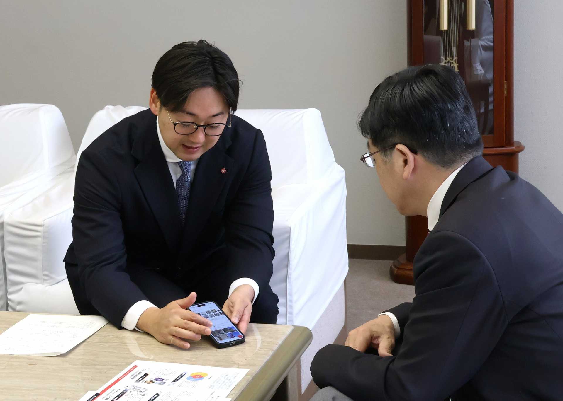 地域コミュニティアプリ「ピアッザ」の説明を受ける山本区長（右）