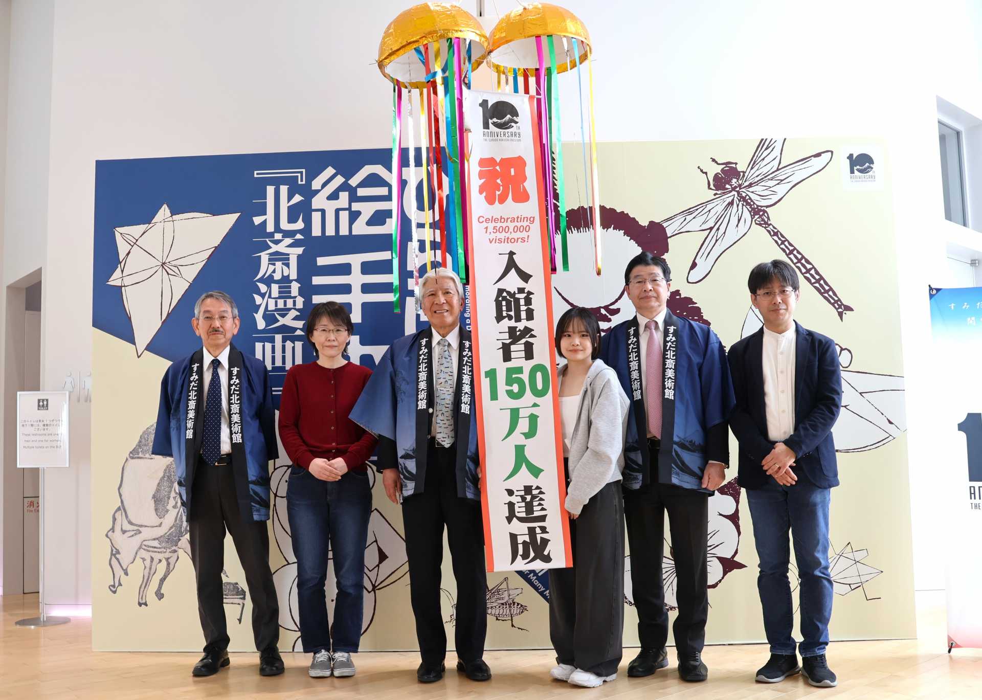「すみだ北斎美術館」総入館者数150万人のセレモニーで、150人目の来館者となった埼玉の女子高生、南和歌菜さん（右から３人目、左から大久保純一館長、南さんの母・祐子さん、墨田区文化振興財団・澁谷哲一理事長、１人おいて山本享区長、南さんの父・知宏さん）