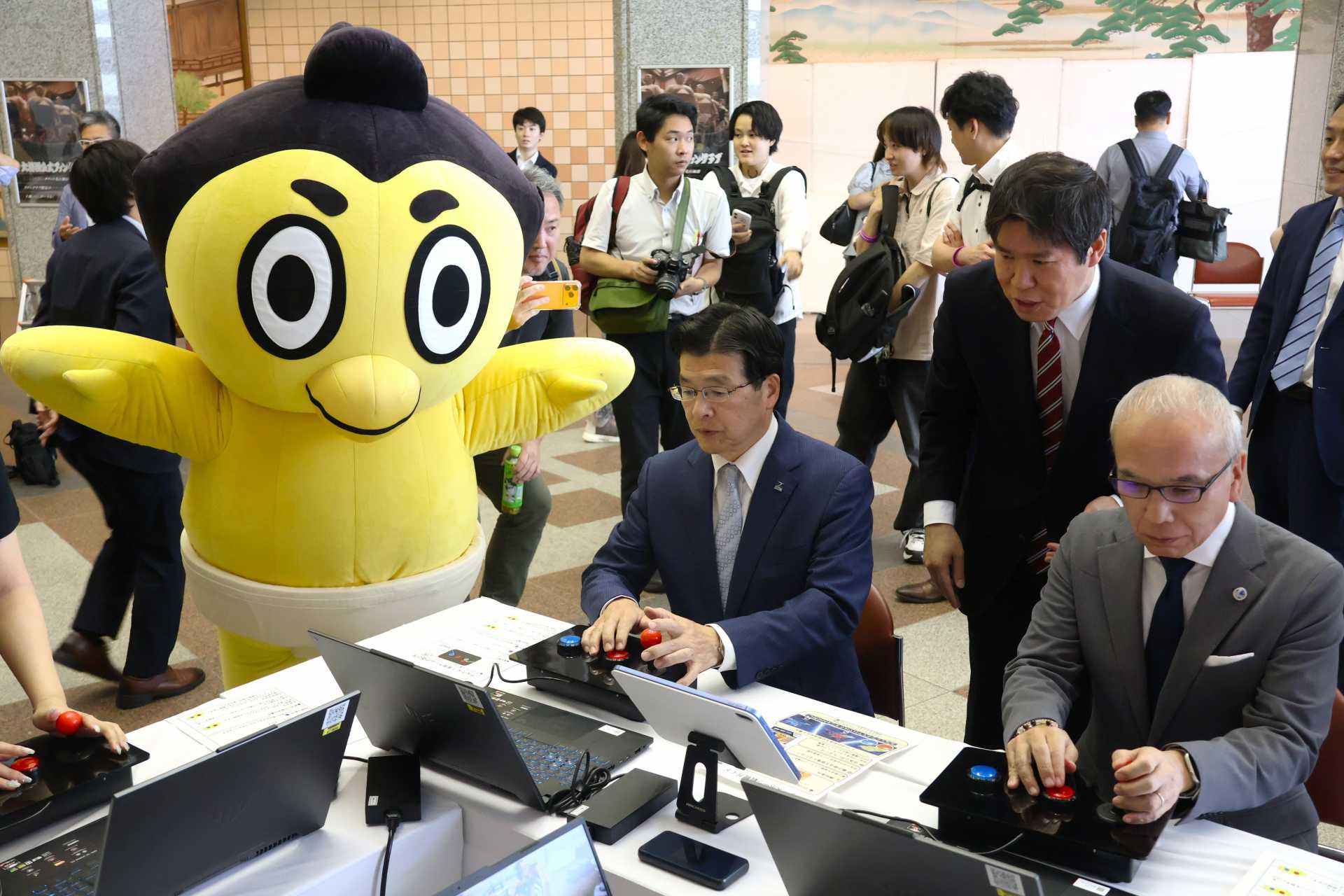 日本相撲協会の公式マスコットキャラクター・ひよの山が見守るなか、ｅスポーツを体験する墨田区・山本亨区長（中央）と学校法人電子学園・多忠貴理事長（右）