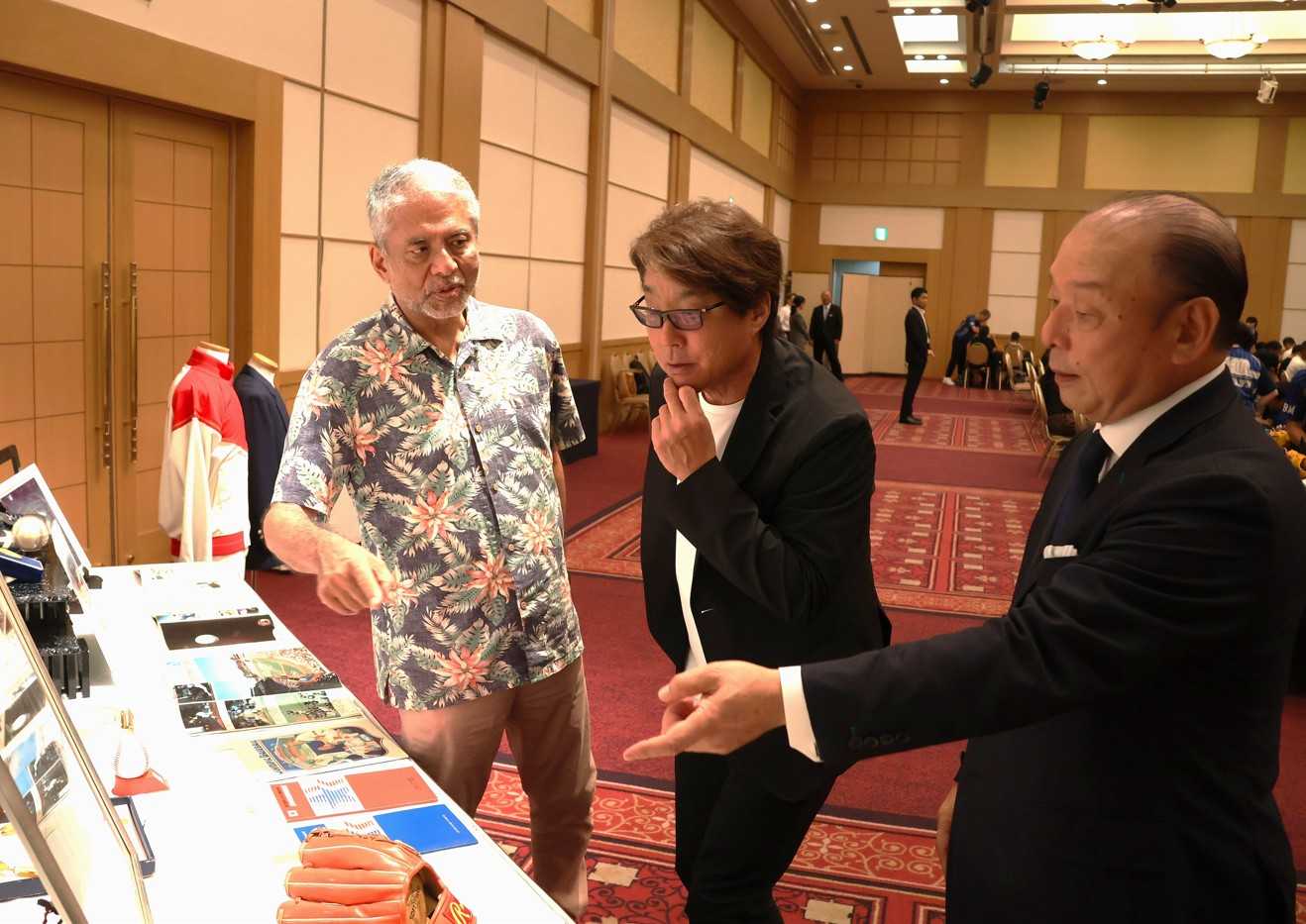 会場に展示されたロス五輪の金メダルなどを説明する吉田さん（右）の話を聞く西プロスカウト（中央）と小西さん（左）