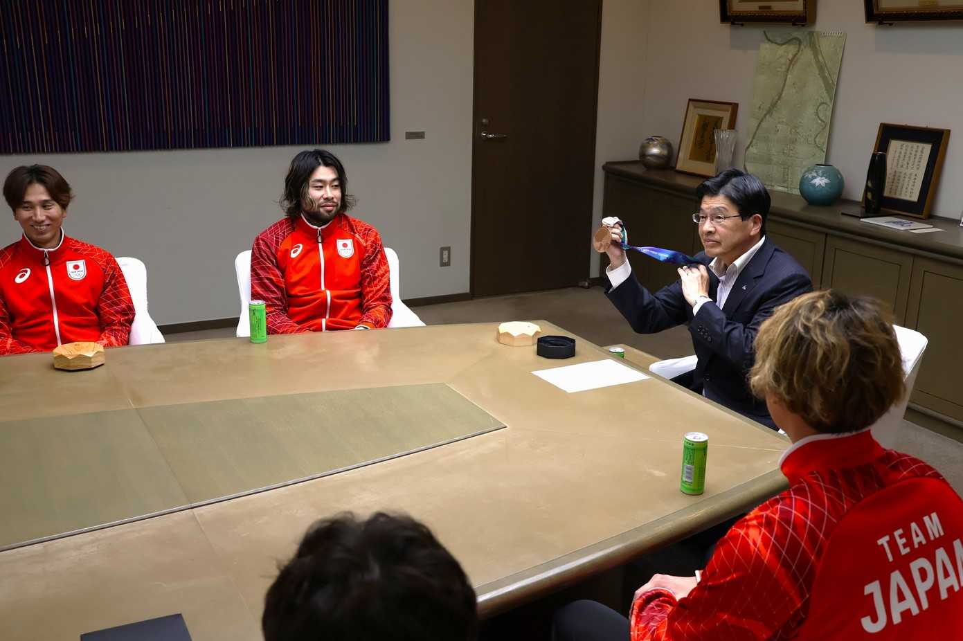 日本代表キャプテン・水町孝太郎（左から２人目）から渡された銅メダルを手にする山本亨区長